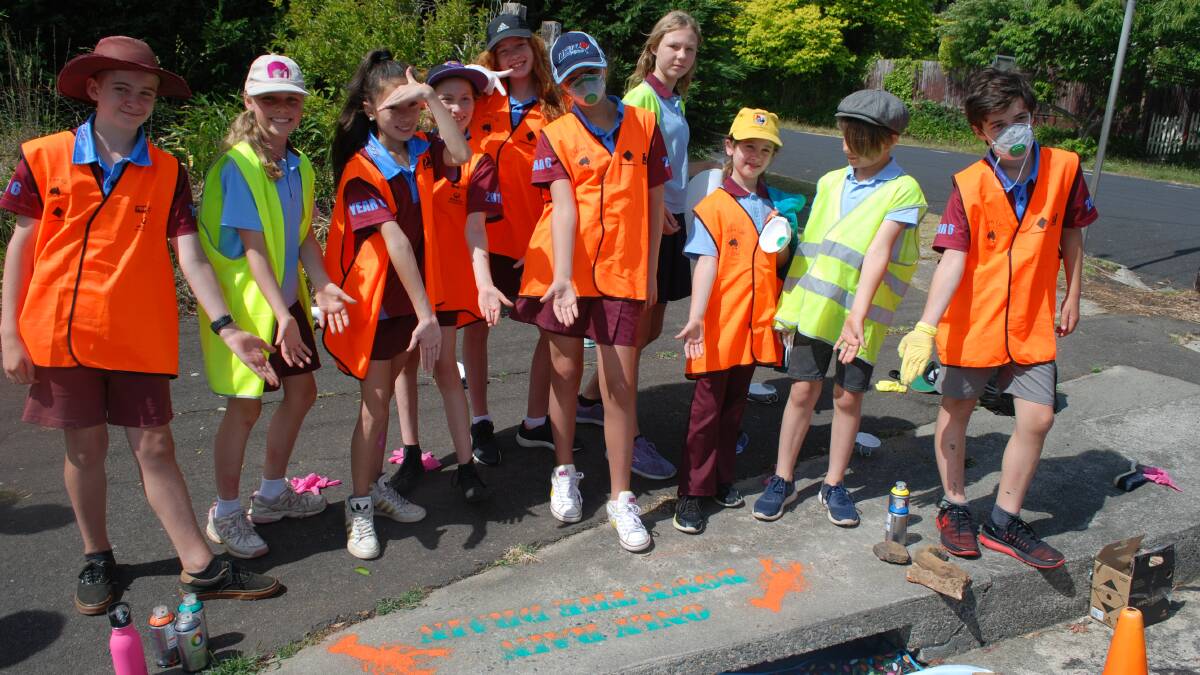 Environmentalists at work: Katoomba Public School's Squid Squad show off the first stencil painted at a drain on Merriwa Street near the school.