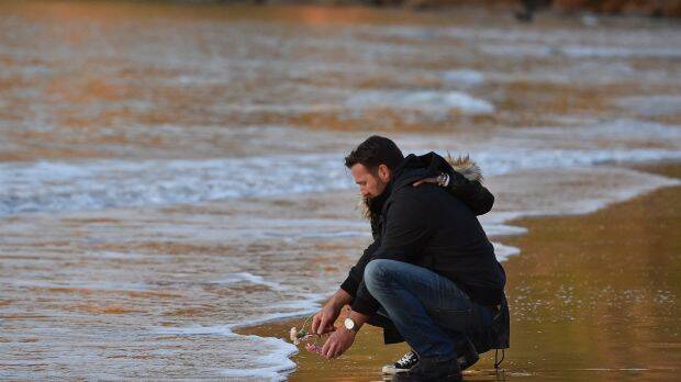 Jason Ruszczyk, Justine Damond's brother, places a flower into the water at Freshwater Beach during a vigil for his sister.  Photo: Kate Geraghty
