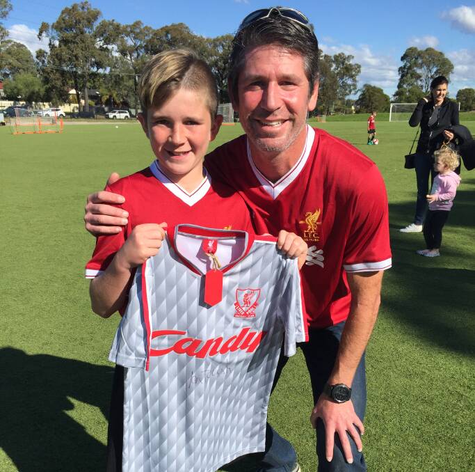 BEAMING: Alex Robinson and dad Scott with the signed Ian Rush jersey he won at Liverpool FC's first Sydney youth academy. Picture: Harrison Vesey