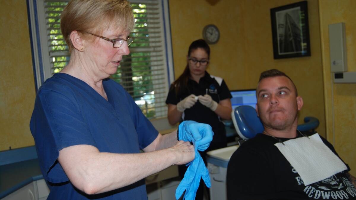 Here to help: Dr Gabrielle Cusack listens to her second patient of the day, Adam Coatsworth, while dental assistant Bethany Donnelly-Single gets ready for treatment.