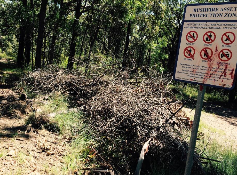Illegal dumping of cleared vegetation within an asset protection zone at Mt Riverview, right next to the sign. It is partially blocking fire trail access. This strip was cleared of understory using the 50m rule and all of the debris pushed into the asset protection zone, according to Mr Bendall.