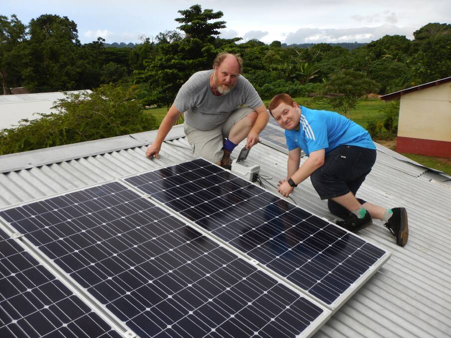 Making a difference: Colin Tyrrell and Alexander Scott make final adjustments to a rooftop solar system they installed in a remote village in Vanuatu.