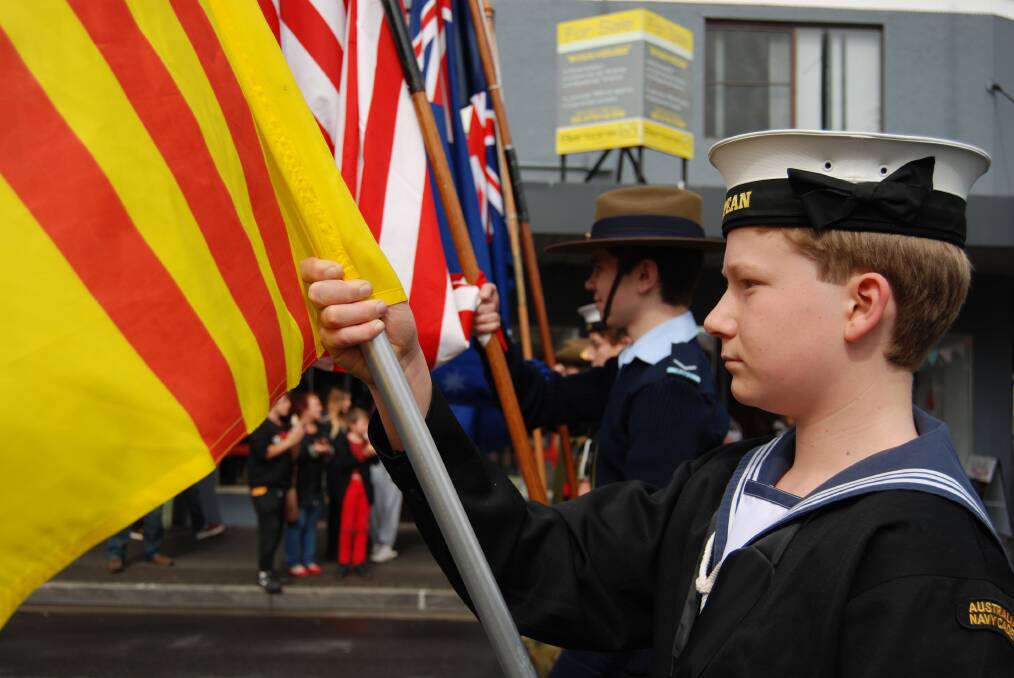 Young navy cadets march on Sunday holding the flags of South Vietnam, United States, Australia and New Zealand.