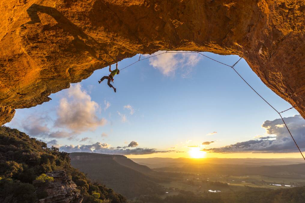 Wow factor: One of the spectacular photos in Leura resident Simon Carter's new guidebook, Blue Mountains Climbing. It shows climber Roman Hofmann clinging onto a natural arch at sunset on a route called Double Adapter near Blackheath.