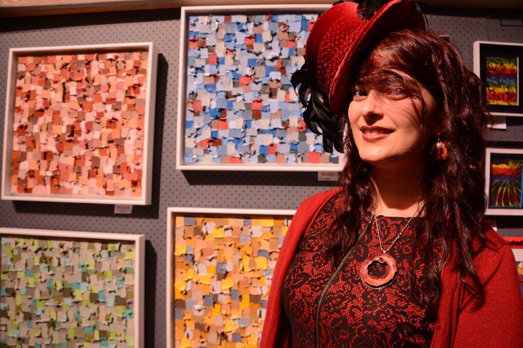 Springwood resident Kirsty Gorman models a hat produced by Christine's Millinery at Winmalee Artfest. In the background are artworks by Jodi McConaghy.
