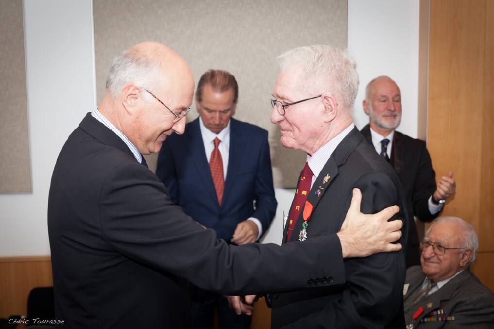 Consul General of France to Australia, Eric Berti congratulates Rex Austin for his service to France after placing the Legion of Honour on his jacket. Photo: Cedric Tourasse