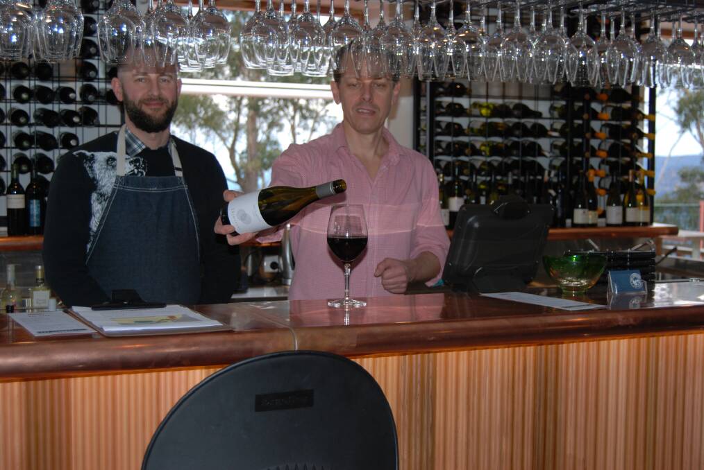 Venue manager Tim Petersen pours a glass of red while assistant manager, Brendan Clarke, looks on in Bar NSW at Echo Point.