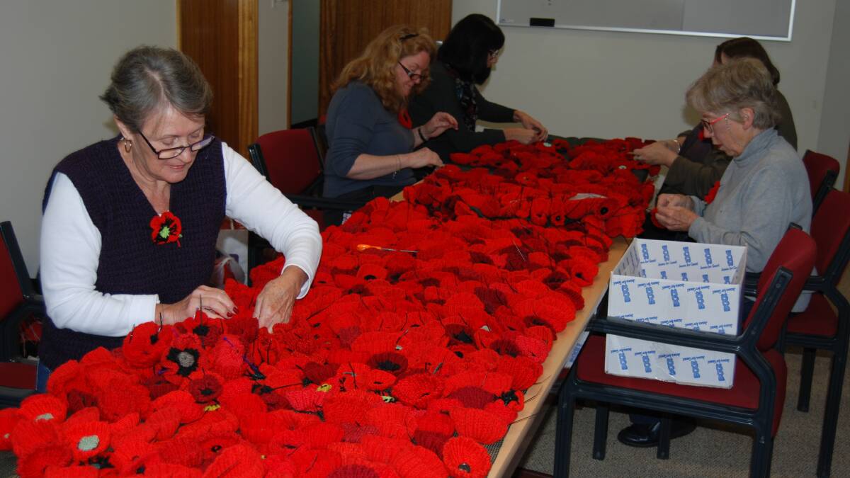Volunteers help attach some of the 12,000 poppies to shade cloth which will be draped in Springwood and Katoomba hospitals to mark the centenary of the Gallipoli campaign. 