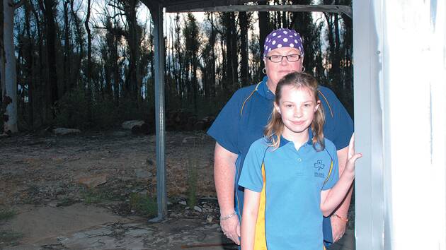 Springwood-Winmalee Girl Guides leader Jasmine Cook with her girl guide daughter Brianna, outside the Guides damaged shed. The Cooks lost their home on Singles Ridge Rd, the same week Mrs Cook was having chemotherapy treatment, but they are looking forward to a visit by the Royals. "They will bring us luck".