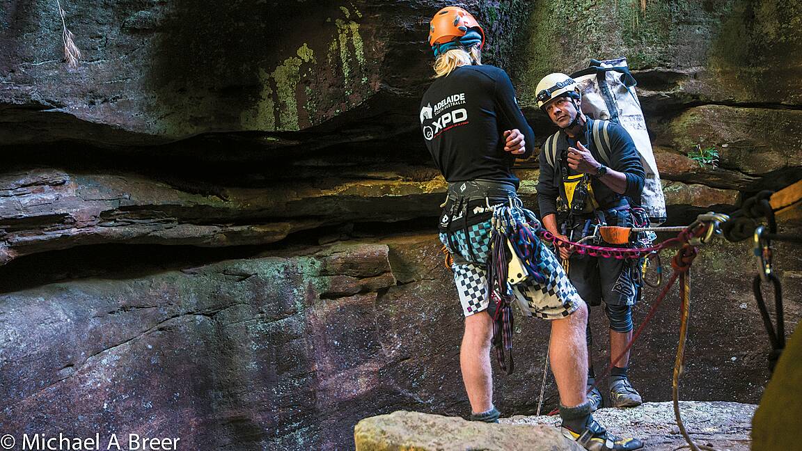 Guide Stewart Hayes and production manager Gilbert Meunier  prepare to abseil into the narrow waterfall section of Claustral Canyon with a load of scanning equipment. Photo: Michael A Breer.