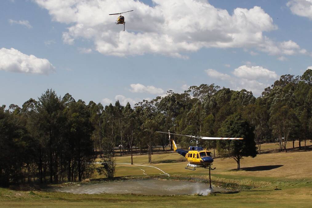 Water bombing helicopters suction water from a dam at the Springwood Golf Course on Wednesday. Photo: Andrew Meares