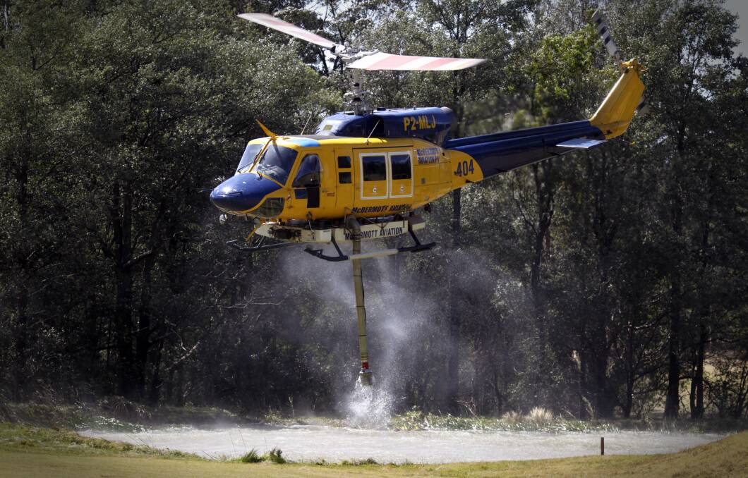 Water bombing helicopters suction water from a dam at the Springwood Golf Course on Wednesday. Photo: Andrew Meares