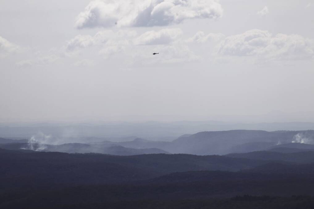 Smoke trails in the Wollemi National Park as a helicopter keeps an eye on the situation. Photo: Nick Moir