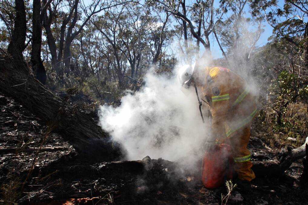 Tim Parsley from Wentworth Falls RFS mopping up after a backburn west of Hat Hill Road in Blackheath in preparation for worsening conditions on Wednesday. Photo: Dallas Kilponen