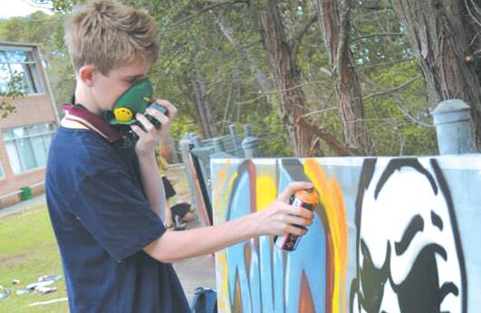 Year 8 student Rainer Rash paints an aerosol art work at Winmalee High School. 