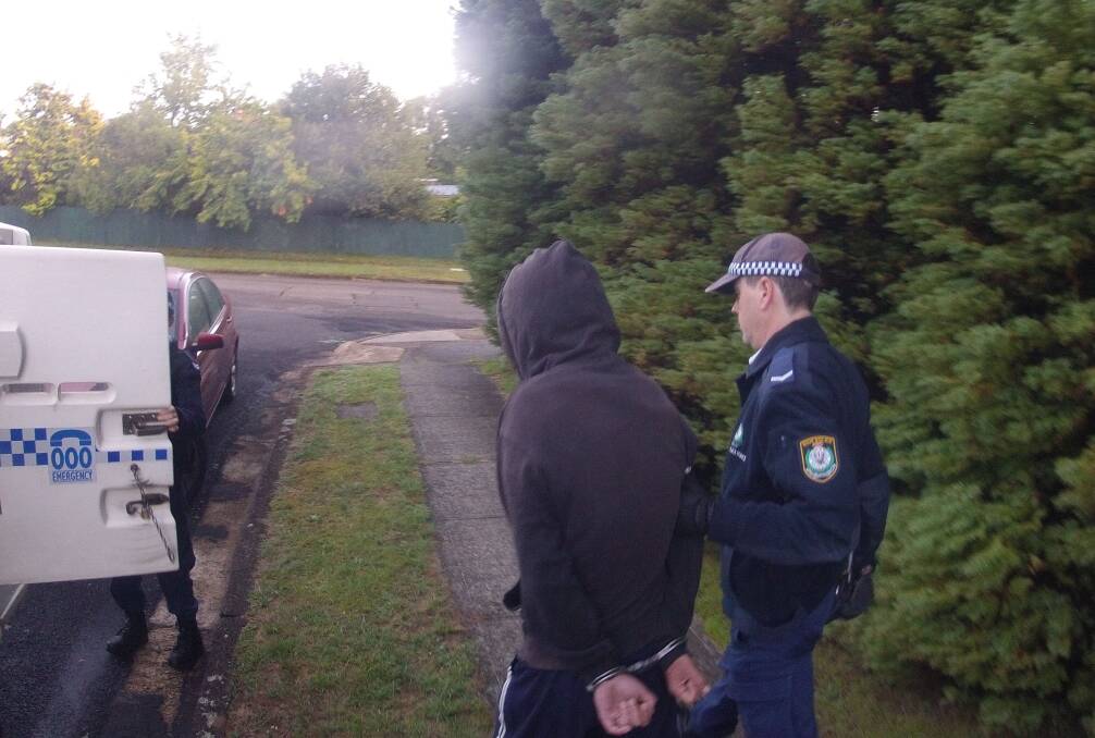 Police lead away one of individuals arrested in drug raids in the Blue Mountain on February 5. Photo: NSW Police Media.