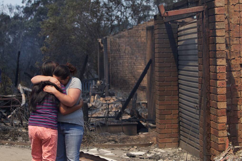 Aftermath of the Winmalee bushfire on Emma Pde. Evangeline Love (left) is comforted by a friend after her home was destroyed in the fire. 18th October 2013 Photo: Wolter Peeters The Sydney Morning Herald