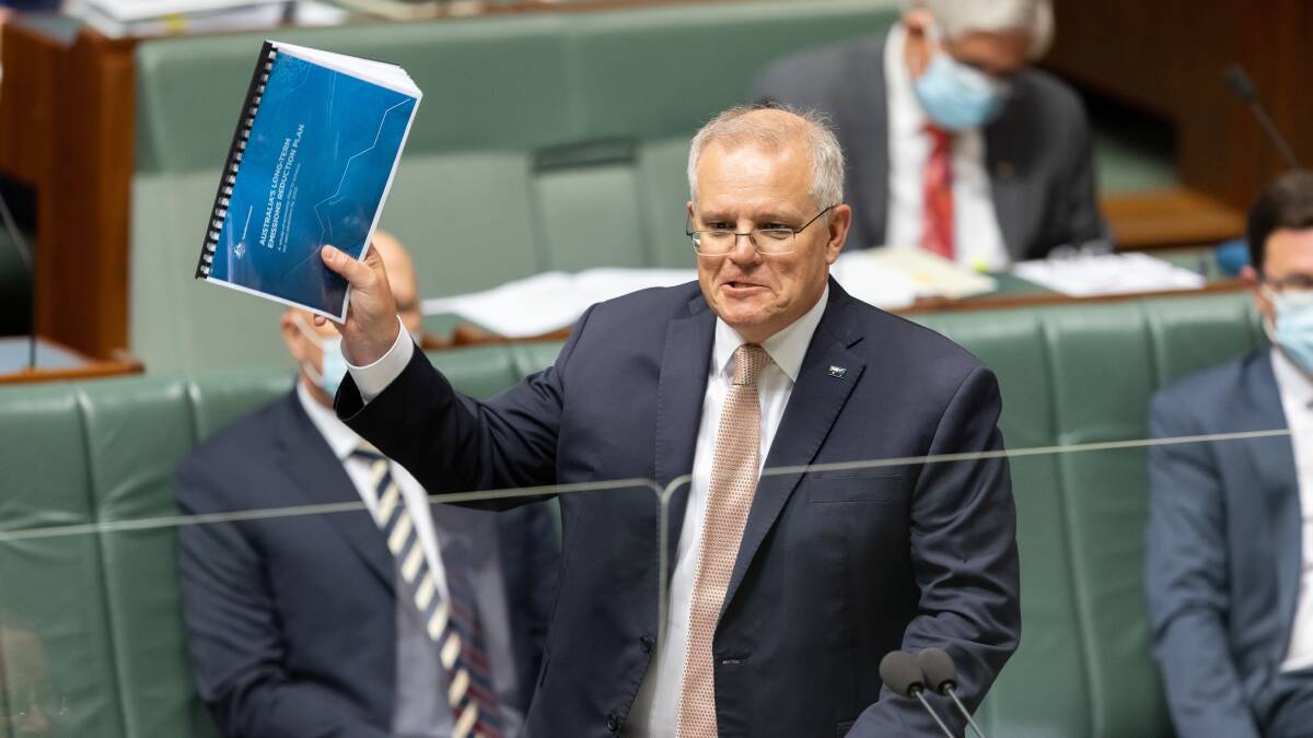 Prime Minister Scott Morrison brandishes a copy of the governments emissions plan during question time on 26 October, 2021. Picture: Sitthixay Ditthavong