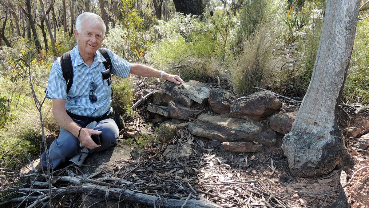 Historic: Author Keith Painter sits beside stonework of the 1916 Heffernans Pass. The lost clifftop track was rediscovered just before the photo was taken by Brian Fox. 