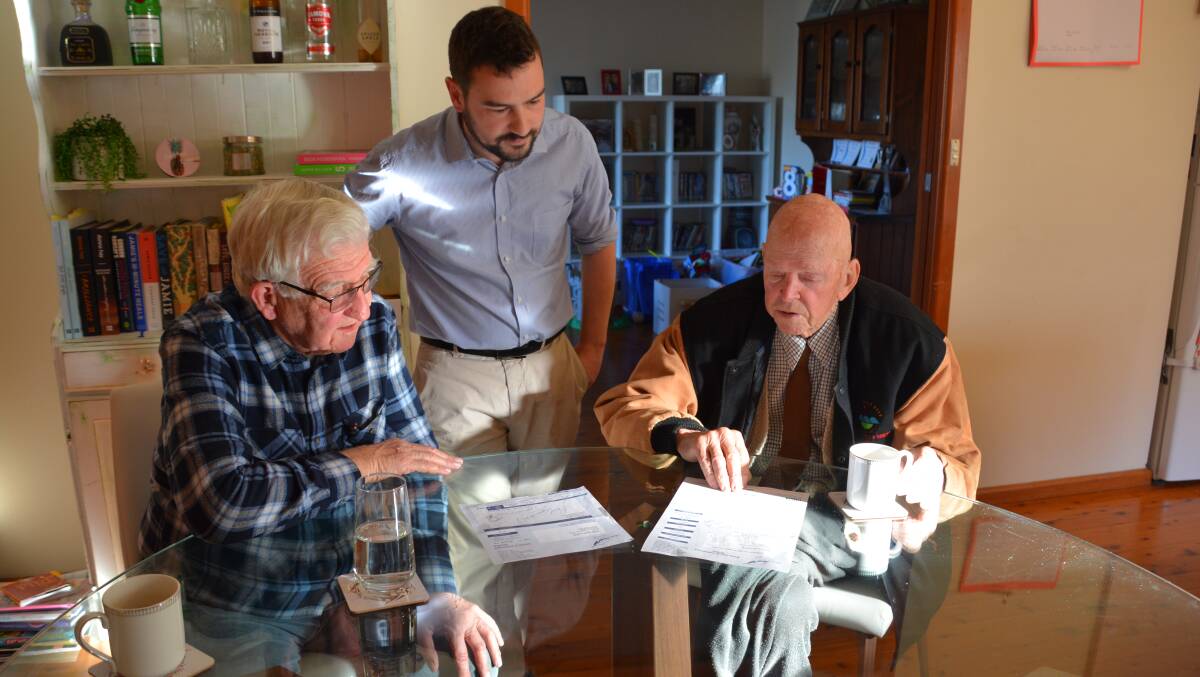 Crs Kevin Schreiber and Brendan Christie with local resident, Bruce Cox, look at recent rate notices.