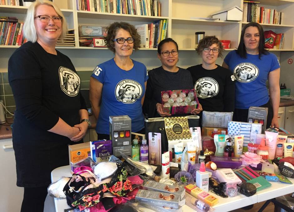 Lisa Donohoe (aka Freda Hounds), Sarah Eberhardt (Kittie Karnage), domestic violence worker Ces Rocha, Cheya Edwards (Maielevolent) and Bernadine Brook (Dr Who Who) with some of the luxuries donated at a recent roller derby tournament in Katoomba.