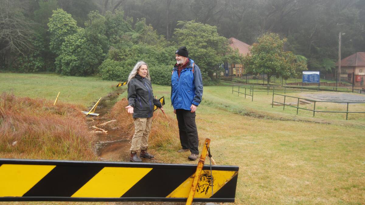 Blackheath locals Eva Johnstone, a landscape architect, and Paul Vale, from Popes Glen Bushcare group standing on the footpath built to the pool which is constantly wet and has been blocked off with council barricades.