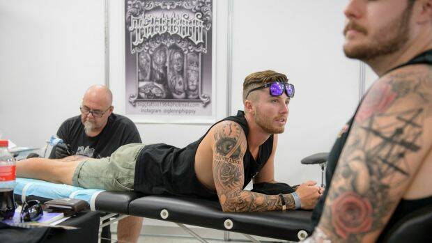Nick Petty from Port Macquarie and Grant Carpenter from Cowra get tattoos from tattooist Glenn Phipps at Summernats on Thursday. Photo: Sitthixay Ditthavong