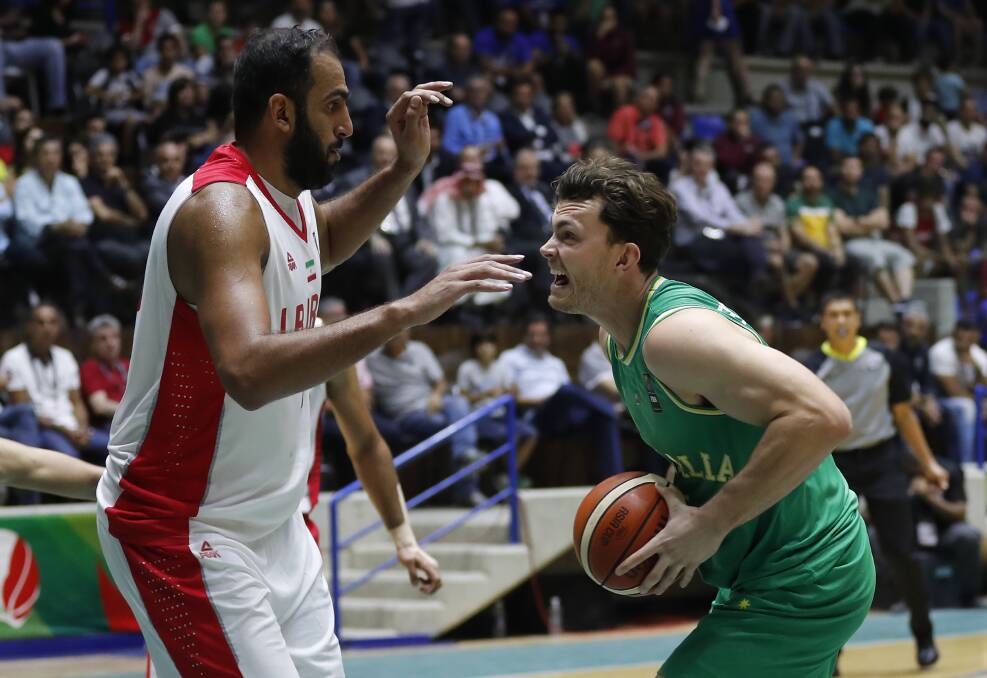 Take that: Australia's Angus Brandt, right, challenges Iran's Hamed Haddadi during the FIBA Asia Cup 2017 final game in Lebanon. Photo: AP/Hussein Malla