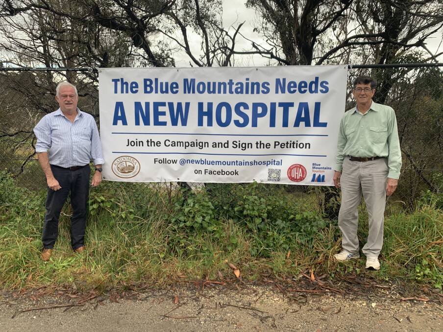 Mark Jarvis, president of Katoomba Chamber of Commerce and Community, with Noel Rath, president of the Blue Mountains Hospital Auxiliary at the sign opposite Katoomba hospital.