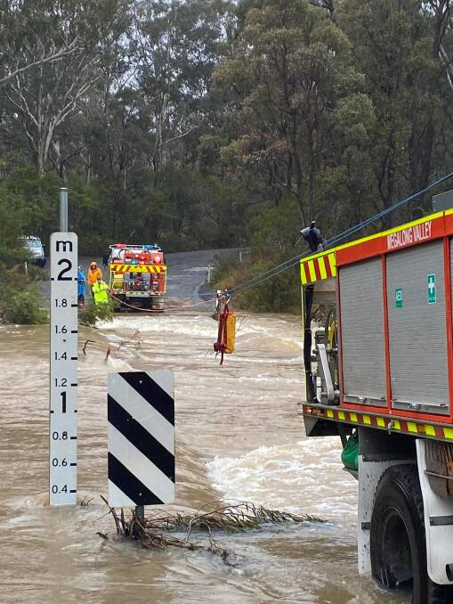 Megalong Valley brigade member Malcolm Scott pulls the emergency rations over the swollen, unpassable Megalong Road at the Old Ford Reserve on July 4 on a zipline.