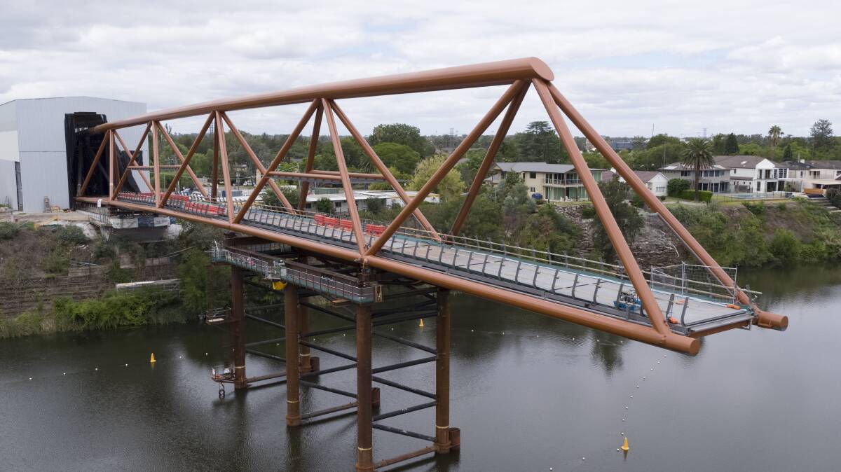 Half way there: Work is ramping up on the Nepean River bridge with another major milestone achieved as the structure reaches hallway across the river.