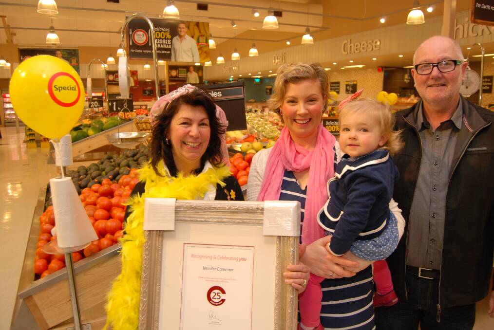 Jenny Cameron holding a certificate of recognition for 25 years of service at Winmalee Coles on August 20, alongside her daughter Laura Murray, granddaughter Luella and her husband Warren.