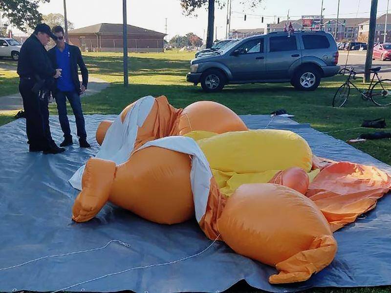 A policeman questions a man after a "Baby Trump" balloon was punctured with a knife in Alabama.