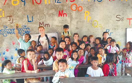 Two Winmalee High mates chose teaching English in Cambodia over schoolies week. Pictured here with their students in the struggling school near Phnom Penh, the pair painted the school concrete wall with English letters as a reminder for the kids.
