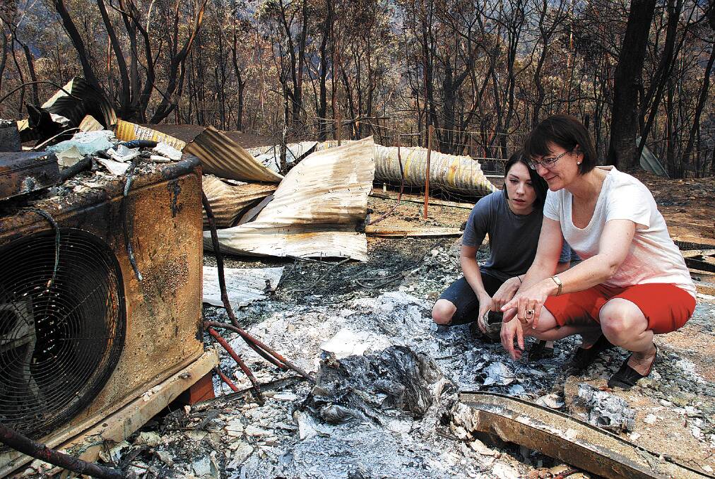  Susan Templeman surveys the remains of her family home in Emma Parade, Winmalee with her daughter Phoebe on Sunday.
