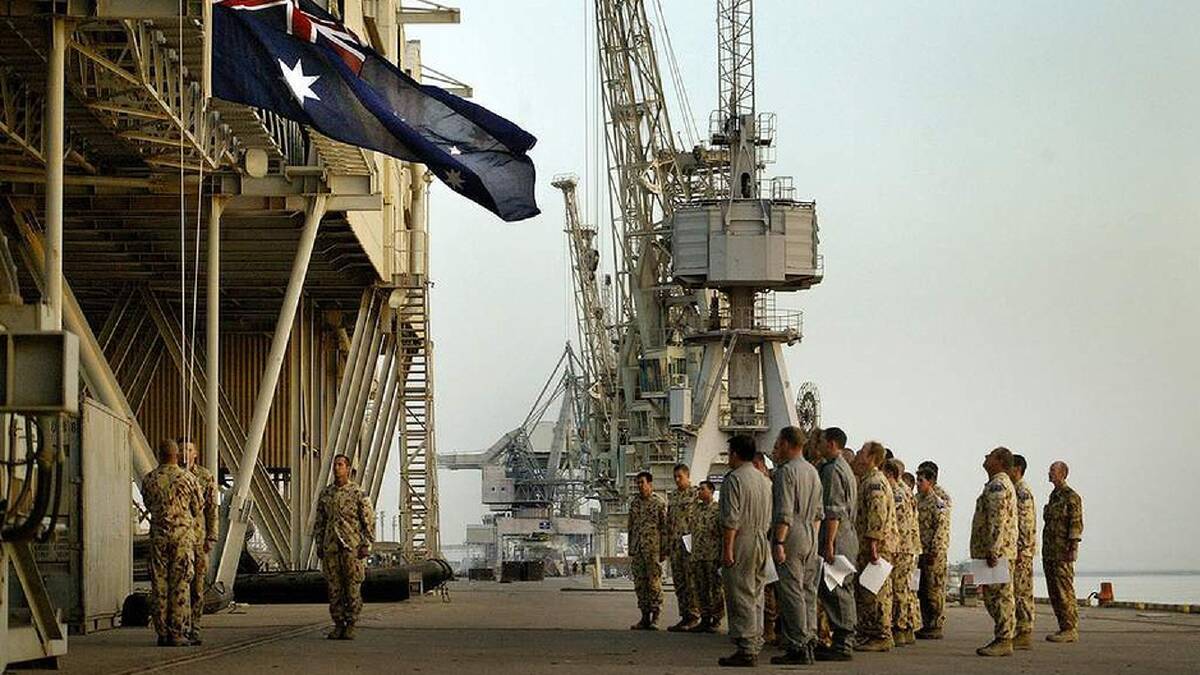 Australian Navy Clearance Divers lower the Australian flag during the dawn service on Anzac Day in Az Zubayr, Southern Iraq, Iraq. 25th April 2003. Photo: Kate Geraghty