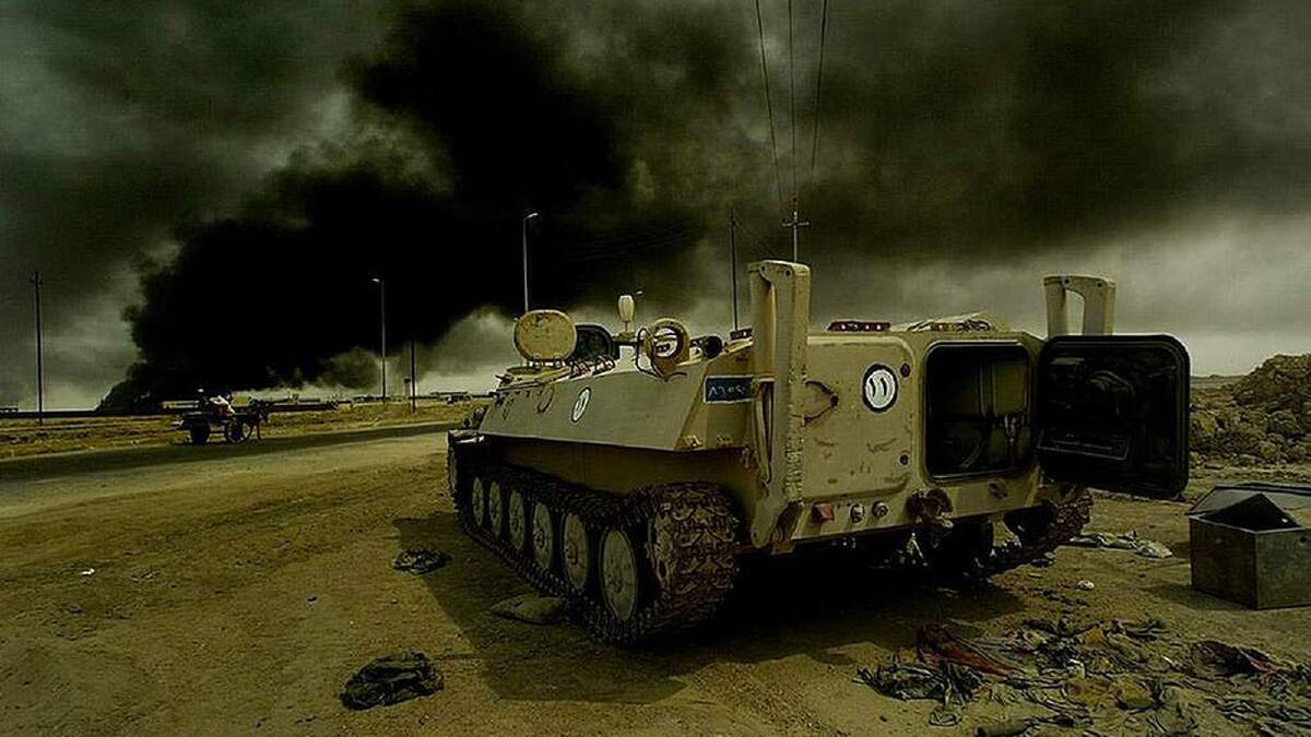 The smoke from an oil fire fills the skies as an Iraqi tank is discarded at the side of the road on the way into Basra, Southern Iraq. 19th March, 2003. Photo: Kate Geraghty