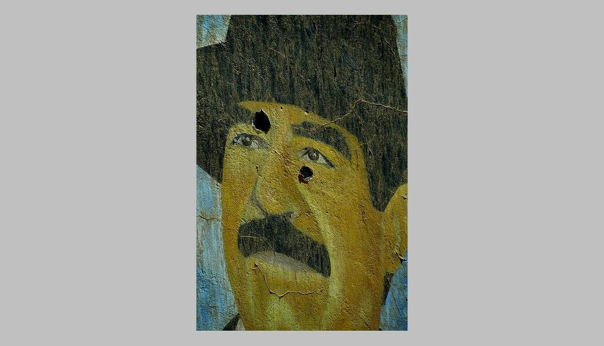 A painting of Saddam Hussein bearing bullet holes. Baghdad, Iraq. March, 2003. Photo: Kate Geraghty