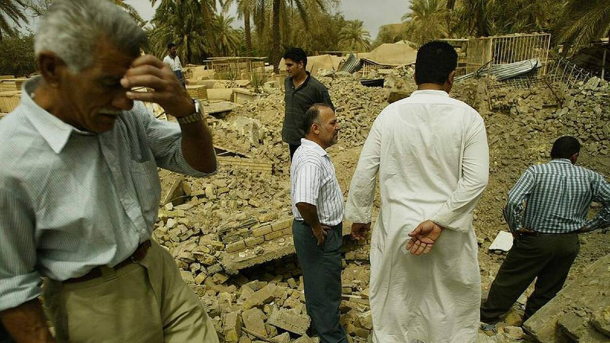 Iraqi men inspect what remains of a graveyard at the rear of a mosque damaged during shelling, central Baghdad, Iraq. Baghdad, Iraq. 20th April, 2003. Photo: Kate Geraghty