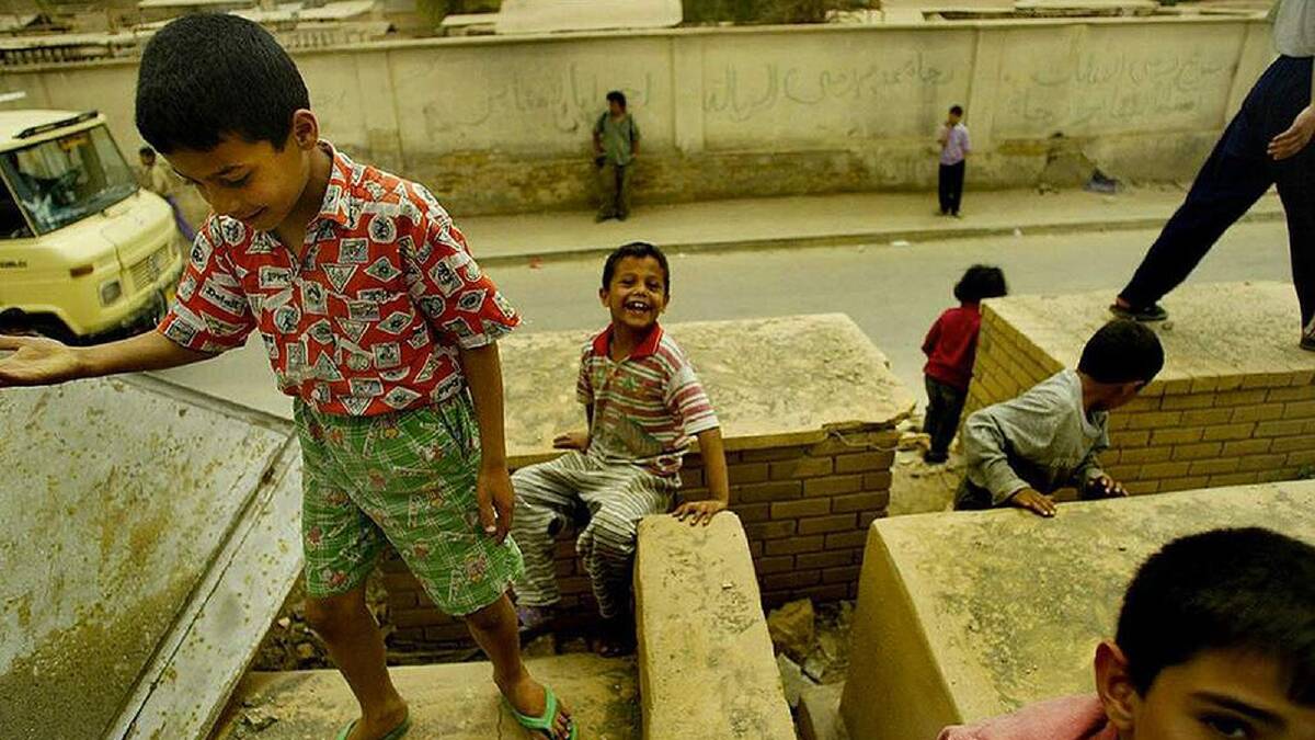 raqi children play on what remains of a graveyard at the rear of a mosque damaged during shelling, central Baghdad, Iraq. Some elements of a normal life is returning to Baghdad. Baghdad, Iraq. 20th April, 2003. Photo: Kate Geraghty