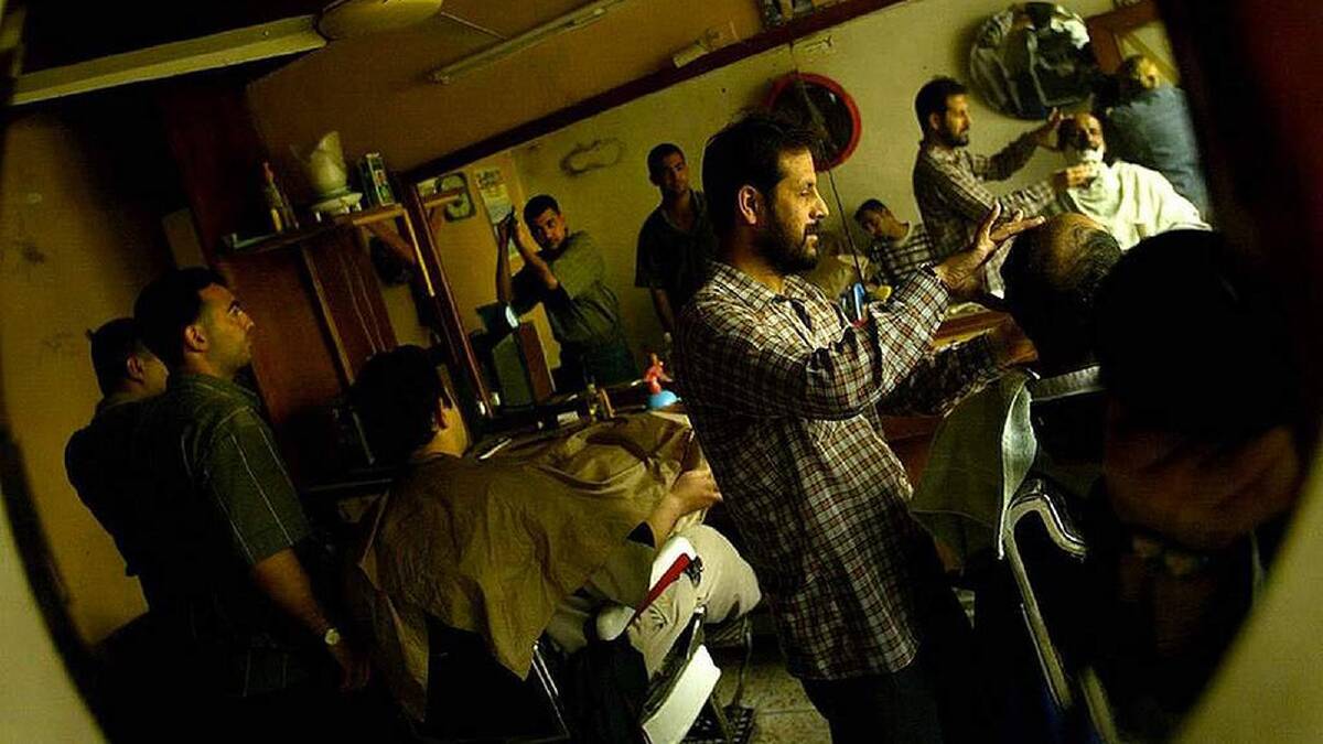 Iraq men gather in barber shops to have their trimmed, socialise and discuss the current status of Baghdad and Iraq. The barber shops are a hive of information and mis-information, the men gather here as there are no jobs. Abu Nuas district, Baghdad, Iraq. 22nd April, 2003. Photo: Kate Geraghty